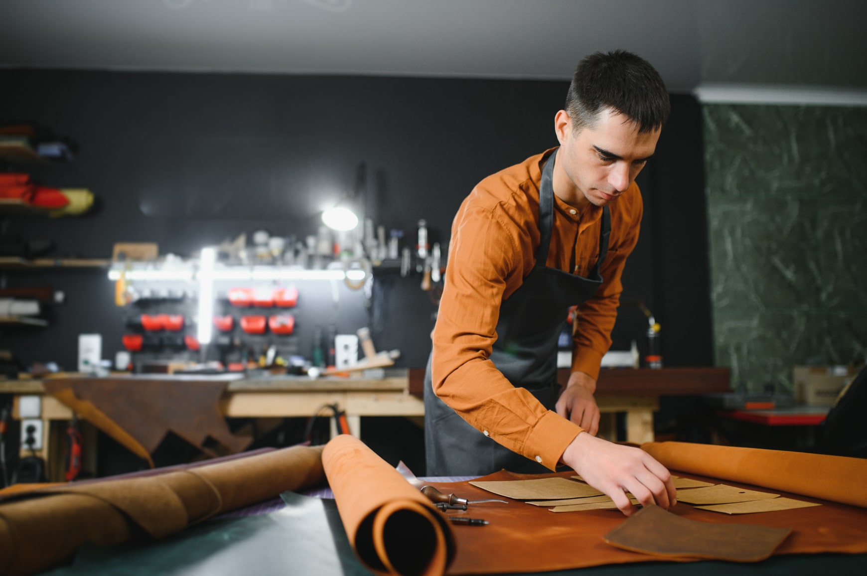 A craftsman working on handmade leather products in a workshop, making products for an online store