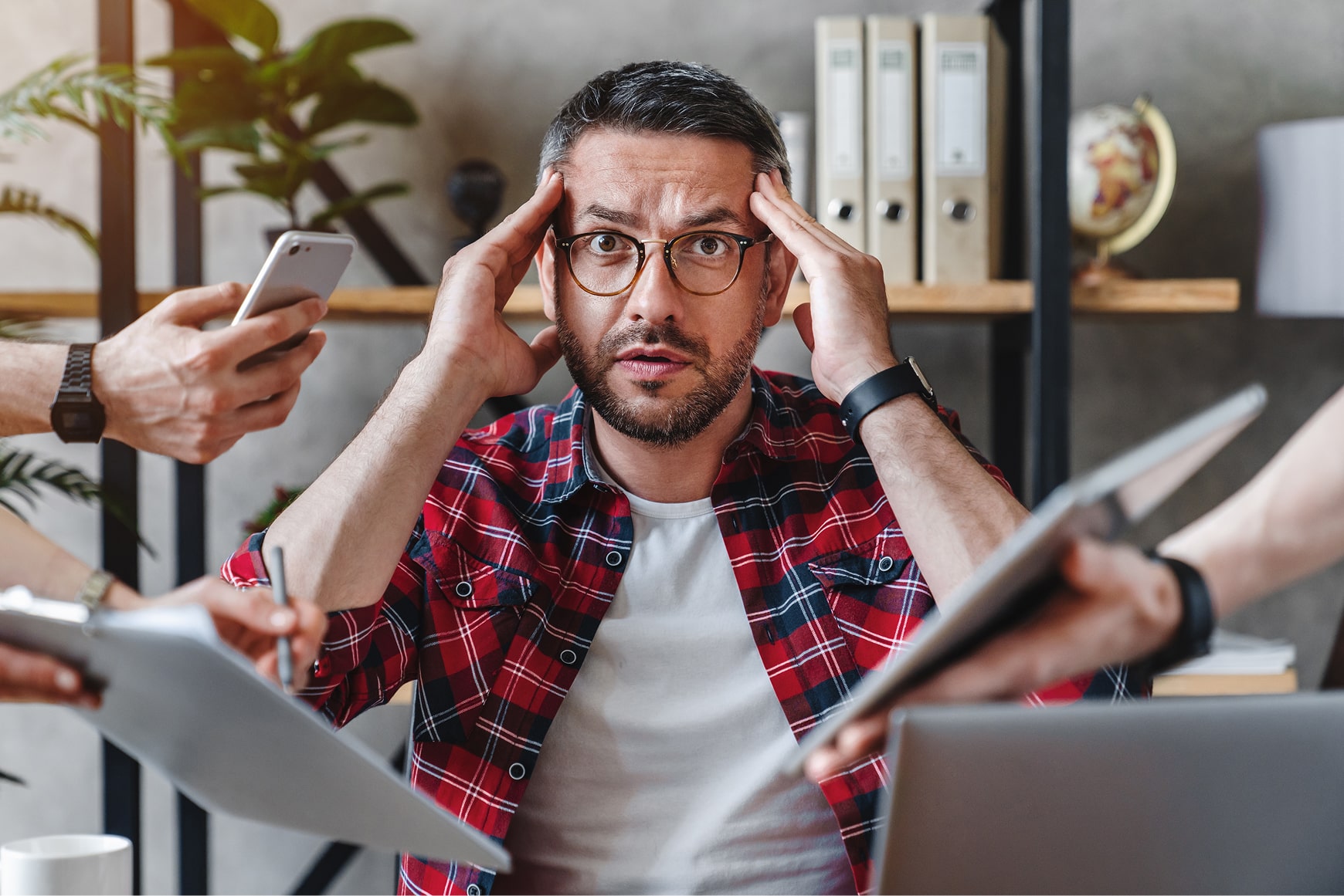 A stressed social media manager holding his head while surrounded by multiple hands holding phones, papers and demands, symbolizing a crisis.