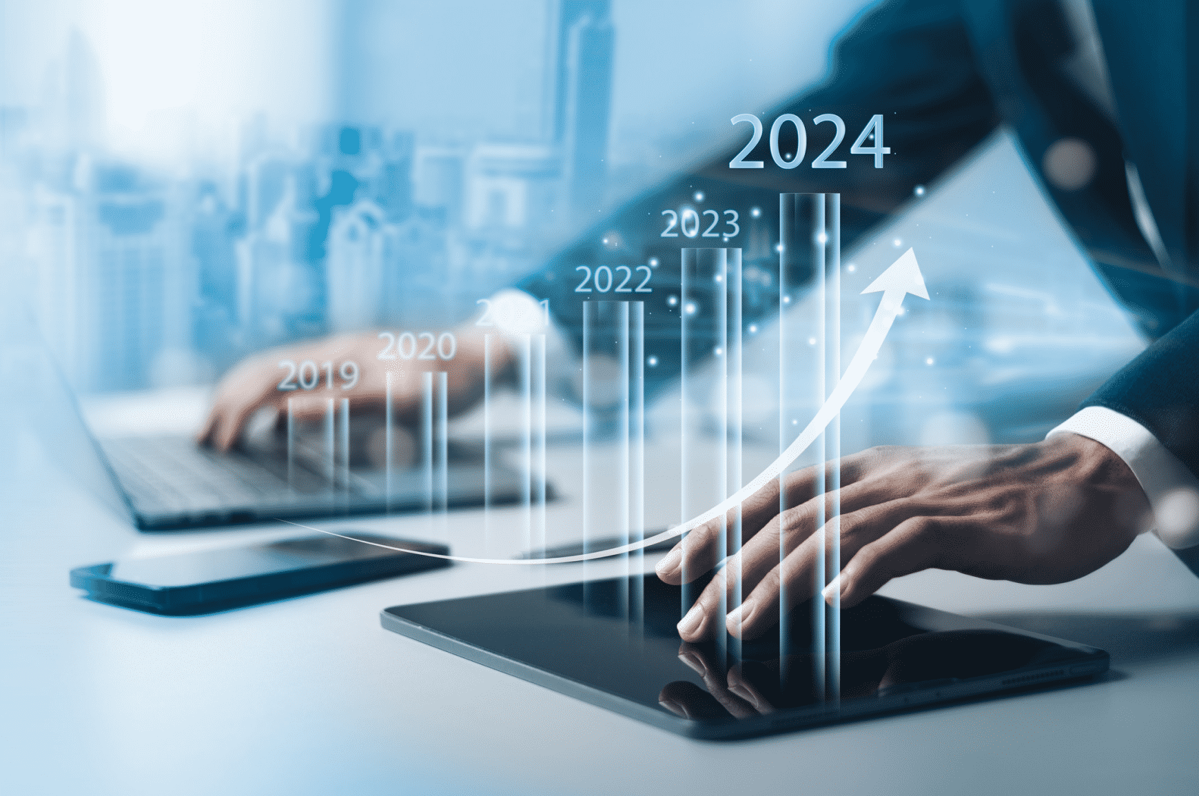 Man with one hand on laptop and other on tablet with holographic bar chart floating on top